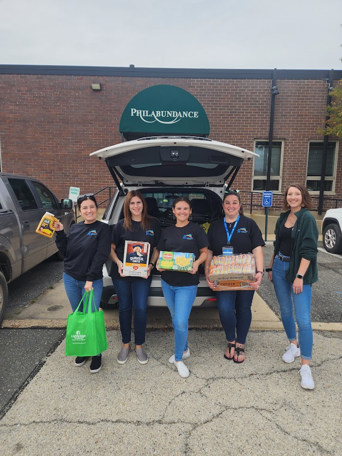 Five people collecting donations outside of a car.