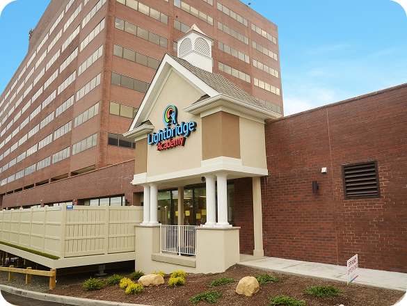 A Lightbridge Academy location near a tall building.