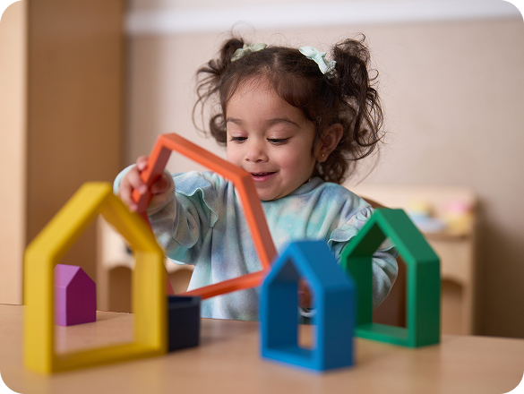A child playing with blocks shaped like houses.