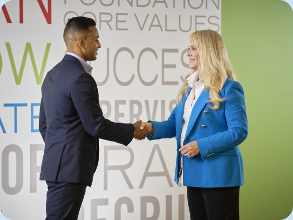 Lightbridge Academy CEO Gigi Schweikert shakes hands with a man.