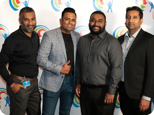 Four men standing standing together in front of a Lightbridge Academy background.