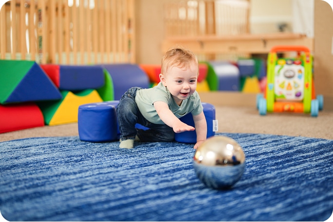 A baby reaching for a ball.