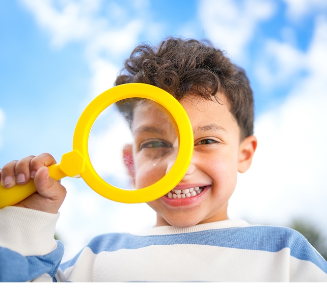 A boy looking through a magnifying glass.