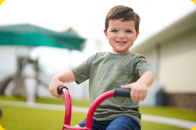A preschool boy sitting on a tricycle.