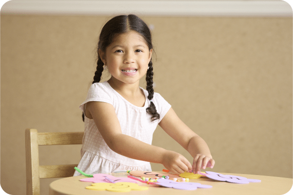 A preschooler sitting at a table doing art.