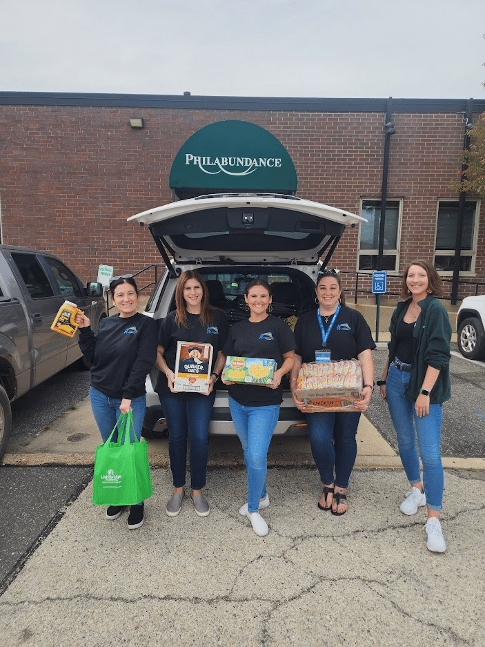 Five people collecting donations outside of a car.