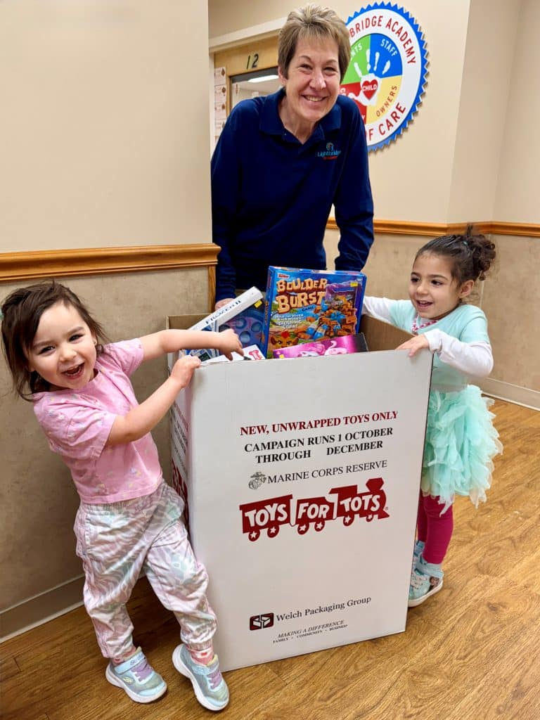 Two children with a Toys for Tots donation box.