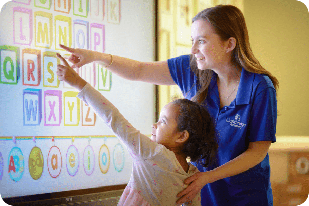 A teacher and child working on a smart board together.