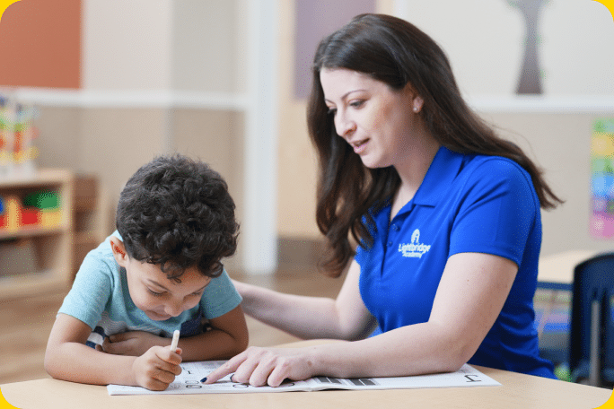 A teacher and a child working on a workbook together.