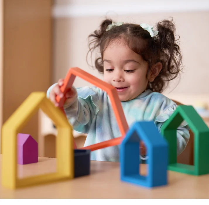 A toddler playing with house-shaped blocks.