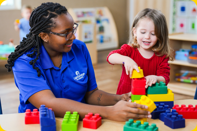 A teacher and child playing with blocks.