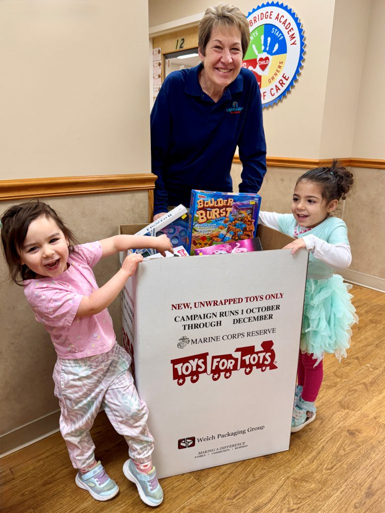 Two children with a Toys for Tots donation box.