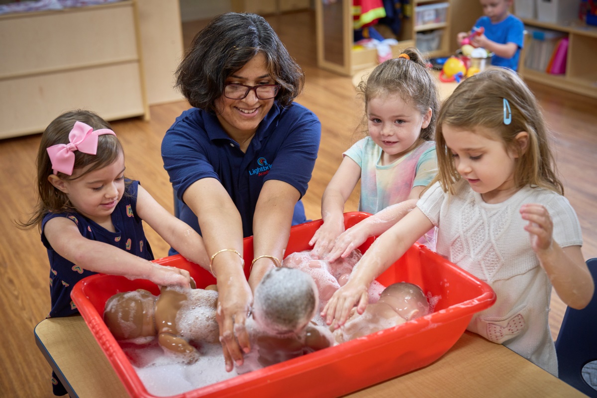 A preschool teacher using dolls to demonstrate bathing techniques