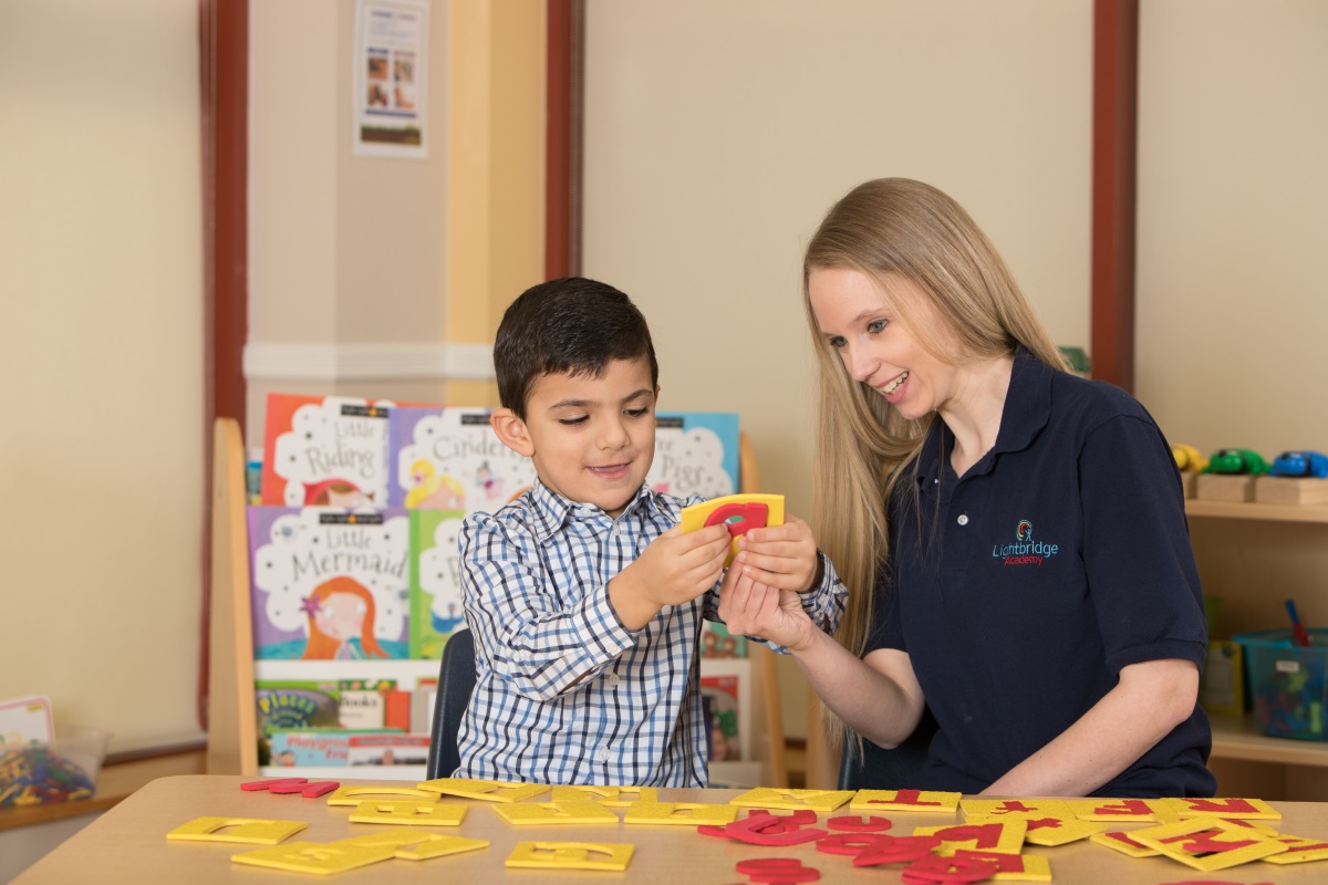 A teacher showing a young child letters