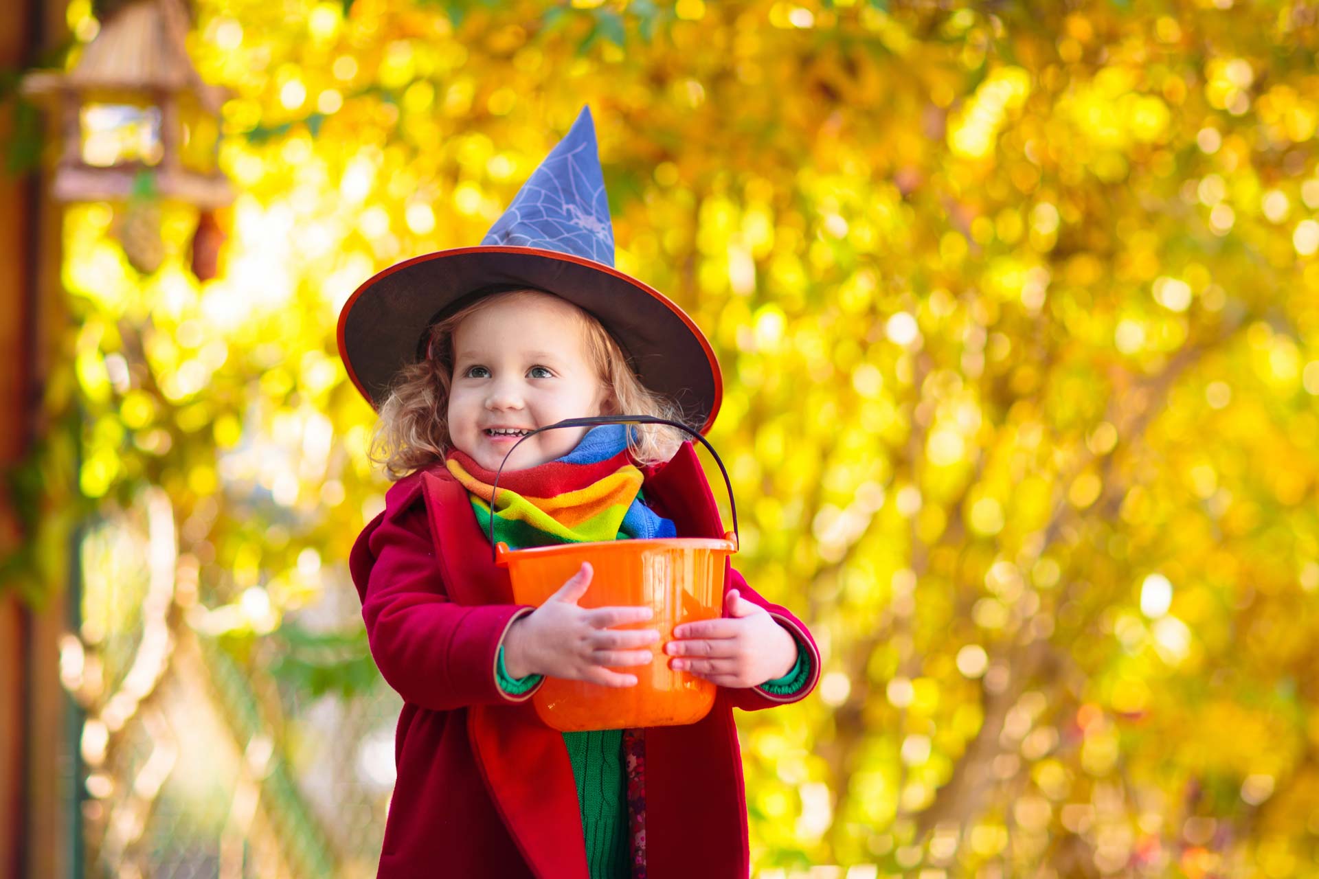 Young girl dressed in Halloween costume holding trick-or-treat bowl