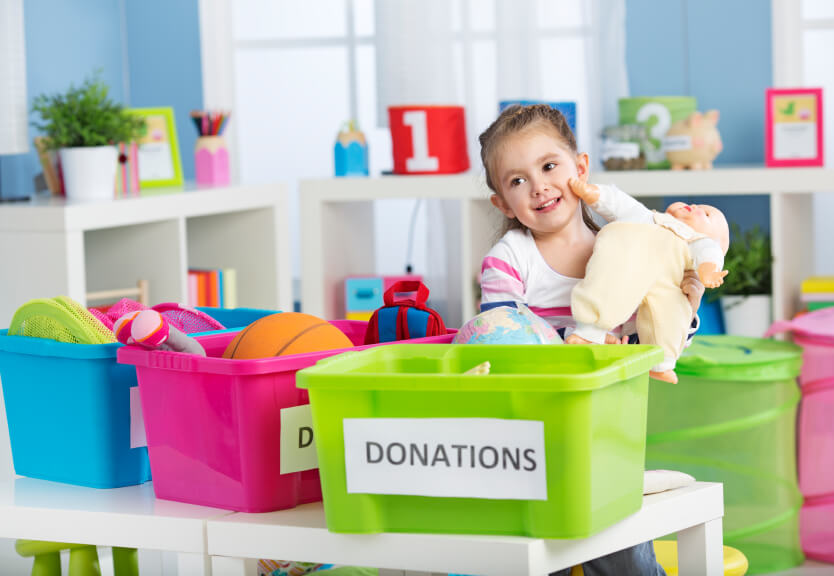 Young child putting toys in a donation box to help out around the house