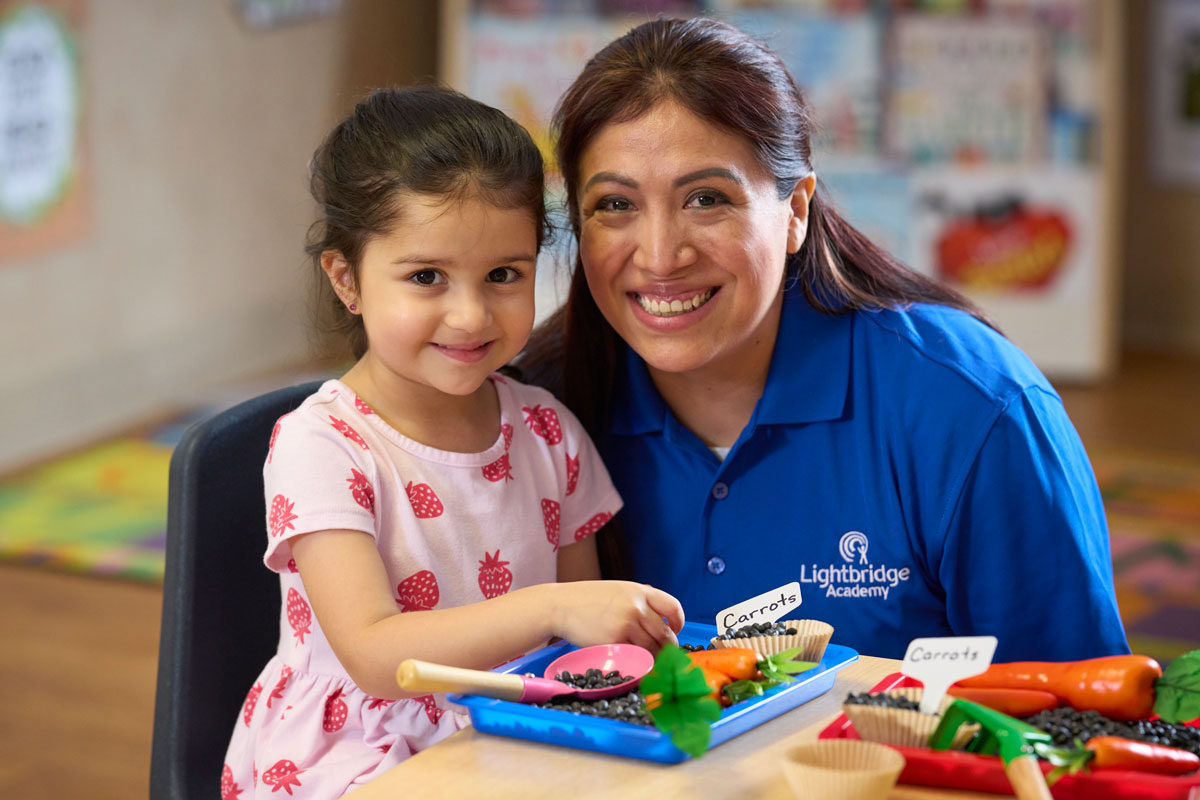 An Lightbridge Academy employee posing with a student learning about their food