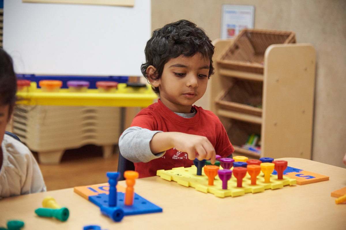 A young boy playing a board game alone