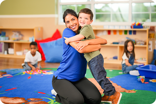A teacher hugging a child in a classroom.