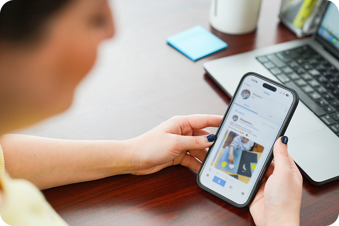 Hands holding a smart phone showing an image of a child in daycare on it.