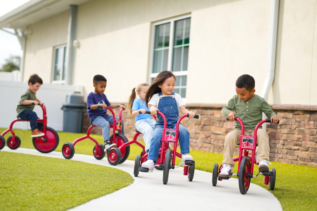 Children riding tricycles outside.