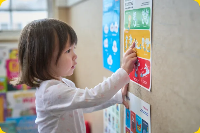 A young child pointing to a picture on the wall.